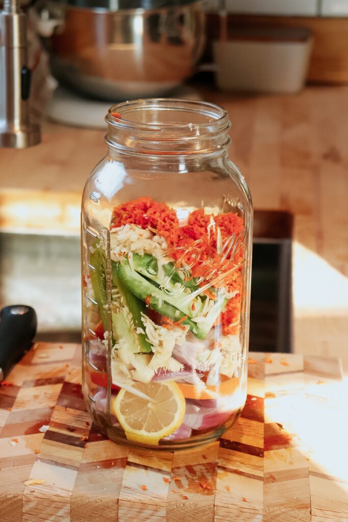 Ingredients to make fire cider sitting in a jar on a counter.